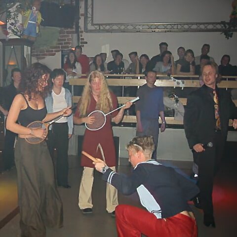 Hypnotisierte Menschen in einer Disco spielen Tennisschläger wie Gitarren